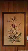 Full view of the needlework art showing embroidered floral and bee design on burlap inside a wood frame.