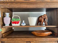 All items arranged on wooden shelf including three ceramic vases, a wooden bowl below, and a wooden elephant figurine.