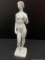 Front view of the white porcelain nude woman figurine with delicate painted facial features and smooth body lines.