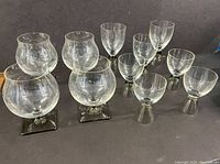 Front and top view of the 7 Fortuna Smoke glasses and 4 Linear Smoke glasses arranged in rows on dark surface.