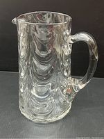 Front view of the clear blown glass pitcher showing wave design and handle