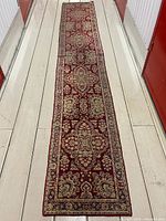 Full length view of the runner carpet laid out on the floor showing overall pattern and colors, with wear obvious.