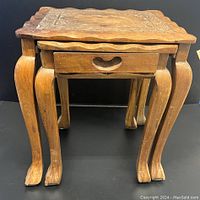Three artisan carved wood tables stacked with smallest two nesting inside each other