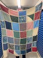 Full view of crochet patchwork blanket showing multiple pastel colored squares and cream borders.