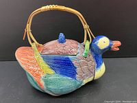 Ceramic duck-shaped teapot in Majolica style, front and side view, showing vibrant colored glaze and bamboo handle.