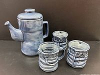 Photo showing full teapot and 3 matching ceramic cups styled with denim jean texture and blue glaze finish.