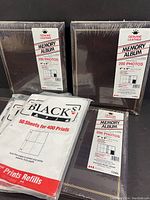 Four vintage genuine leather memory albums sealed in original plastic packaging. Each album holds 200 photos sized 4x6 inches. Three white packages of Black's photographic photo print refills for 4x6 photos, labeled for 50 sheets and 400 prints total.