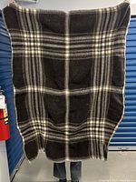 Full view of the wool blanket held up, showing the brown and cream plaid pattern.
