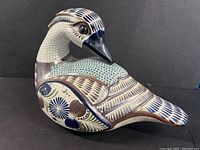 Side view of large ceramic duck showing detailed hand-painting with blue, brown, white, and green patterns.