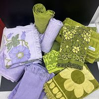 Overall assortment of green and purple floral towels showing various sizes, patterns and textures.