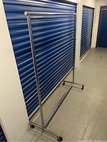 Full side view of the stainless steel garment rack showing its height and horizontal hanging bar.