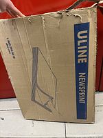 Front view of the worn cardboard box with Uline Newsprint branding