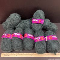 Group of nine skeins of dark greenish-grey vintage mohair blend yarn in a row with purple Phildar Vizir labels.