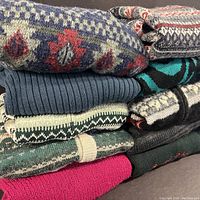 Stack of vintage knit sweaters showing various patterns and colors including fair isle and Aztec Navajo patterns.