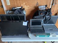 Photo shows the Vizio monitor, 3 vintage laptops, camcorder in case, cables and accessories on table.