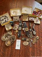 Overview photo of entire assortment of costume jewelry and watches on wooden table.