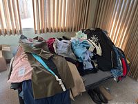 Photo of assorted clothing items including jackets, shirts, and a pair of shoes on bed.