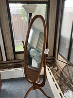 Front view of the wooden oval cheval mirror, showing its reflective surface and curved stand.