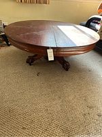 Full view of round coffee table showing dark brown wood grain top and four clawfoot legs.