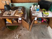 Two wooden side tables with various items placed on top and in shelves, including glass ashtrays, stuffed animals, and game sets.