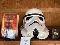 Photo showing Star Wars Planet of Twilight book, white Stormtrooper helmet, and Star Wars trading card box on shelf.