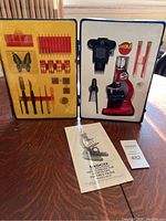 Full view of open Tasco microscope kit including microscope, accessories, and instruction manual in case.