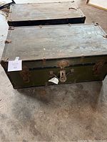 Full view of both large vintage trunks stacked, showing condition and locking hardware