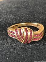 Angled view of ring on black textured surface showing crossover design and amethyst rows