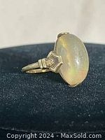 Front angle of ring showing large oval cabochon stone and gold shoulders