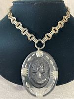 Front view of the sterling silver Art Deco choker with large clear acrylic pendant featuring an etched black profile of a woman, displayed on a black bust.