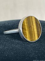 Front view of sterling silver ring with round tiger eye stone featuring chatoyant golden-brown bands.