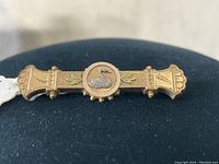 Front view of the Victorian rose gold pin with silver swan center and green leaf accents on black background.