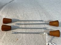 Four vintage cocktail forks laid out to show full length, brown Bakelite handles and metal fork prongs. Shows the overall look and size.