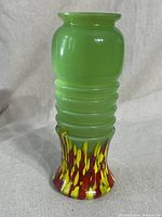 Full view of the vintage jadeite glass vase showing ribbed body and multicolor splatter base.