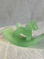 Side view of the jadeite terrier rocking figurine on fabric background.