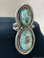 Front angle showing two oval turquoise stones with rope pattern silver framing and bead accents on a double band sterling silver ring.