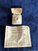 Miniature Krugerrand coin in blue velvet display box with certificate of authenticity.