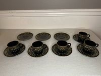 Full set of four demitasse cups and four matching saucers arranged on a surface, showing the entire lot contents.