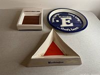 Display of two porcelain ashtrays and one tin tray on grey surface