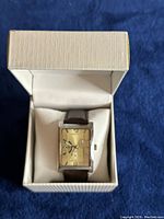 Watch displayed in its original hinged presentation box on blue cloth background