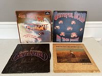 Four vintage vinyl albums with some wear to covers. Includes albums by Joe Walsh, Grateful Dead, John Fogerty, and Tom Petty & the Heartbreakers.