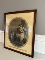 Framed etching artwork displayed propped against a wall showing full piece with matting and frame.