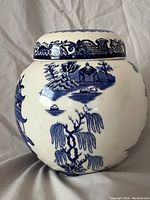 Front side of the tea caddy showing a scene with a small house, trees, and pagoda in blue transferware.