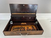Open pine wood tool box showing inner tray with wooden letters and two glass ink bottles in compartment inside lid.