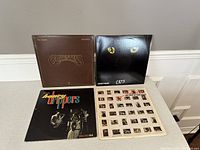 Four vinyl album covers arranged, visible titles include The Beatles 'Chesnuts', Cats soundtrack, The Honey Drippers 'Volume One', and an album with photo insert