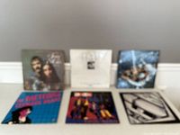 Blurry photo showing the six vinyl record covers, some with portraits, others with band imagery and abstract art.