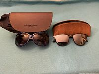 Two pairs of sunglasses side by side with their respective cases, showing overall condition and accessories