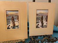 Two matted watercolour paintings showing rocky coastal scenes under cloudy sky, both signed and dated.