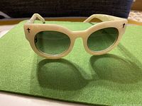 Front view of pearl white acetate sunglasses with round grey lenses and black cross inlays