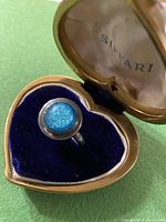 MCM sterling silver ring with round iridescent blue stone in heart shaped ring box with blue velvet interior.